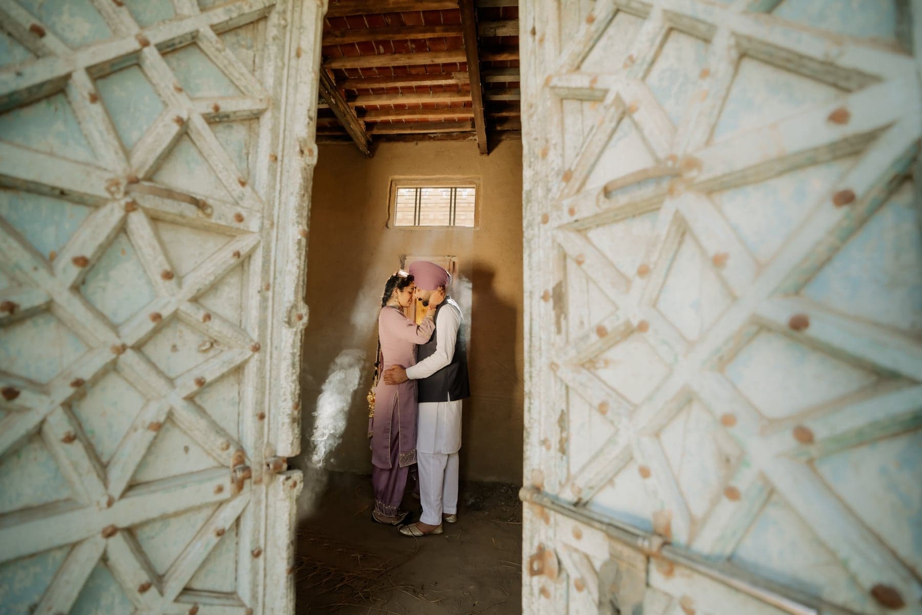A couple photographed together against a weathered red wall